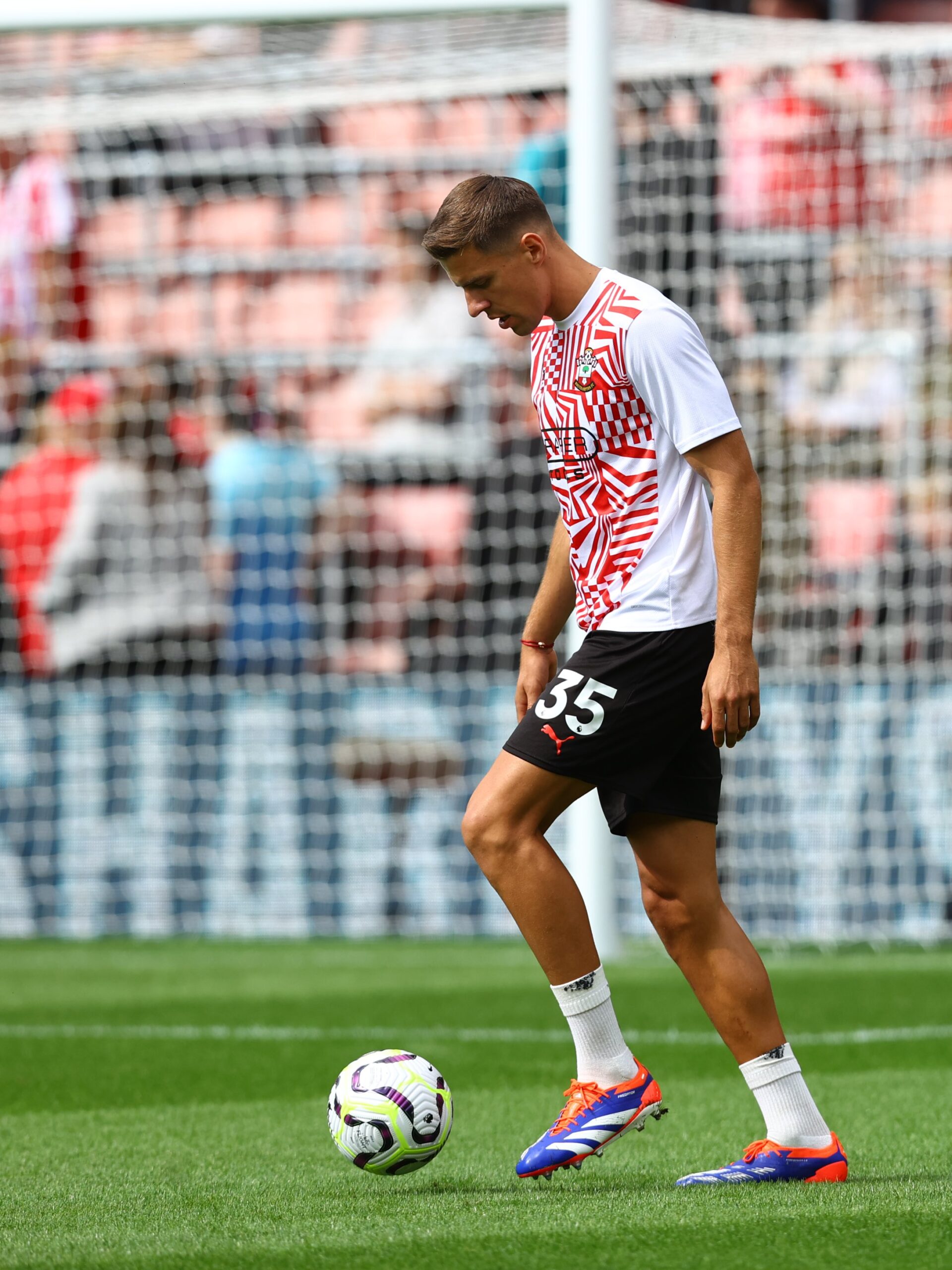 Jan Bednarek dribbles the ball during warm-ups at St Mary's Stadium, wearing a red and white warm-up shirt with black shorts.